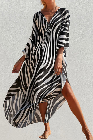 A woman wearing a V-neck black and white kaftan dress at the beach.