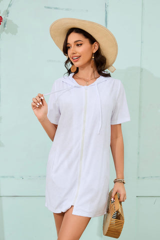A woman wearing a white zipper hooded swimsuit coverup with pockets.