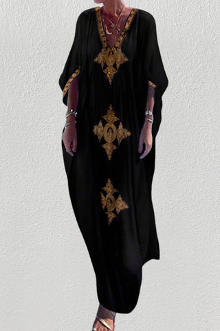 A woman wearing a black v-neck kaftan summer dress at the beach.