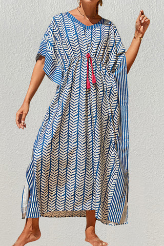 A woman wearing a blue cheap kaftan dress with sun glasses at the beach.