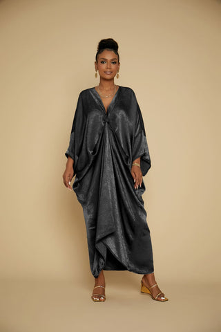 A Black woman is wearing a black satin V-Neck caftans coverups and a necklace.