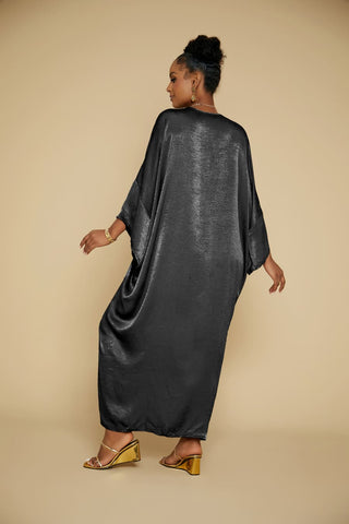 A Black woman is wearing a black satin V-Neck kaftan coverups and a necklace.