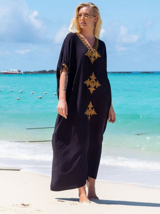 A woman wearing a maxi short sleeve kaftan summer dress at the beach.