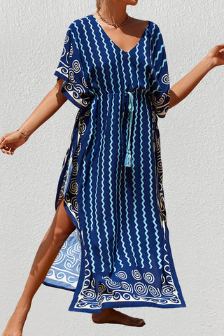 A woman wearing a stripe kaftan dress with a hat at the beach.