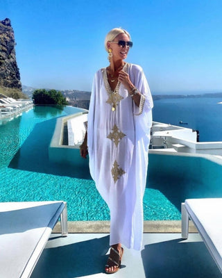 A woman wearing a white v-neck kaftan pool cover up.