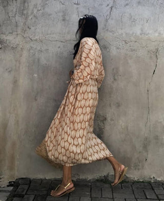 A woman wearing a yellow leaf kimono cardigan with a bag.